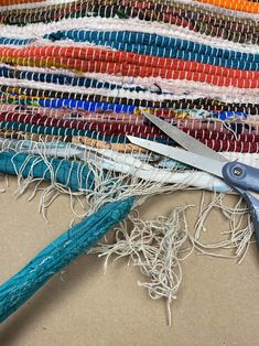 a pair of scissors sitting on top of a pile of colorful thread and yarns