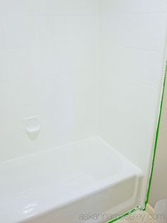 a white bath tub sitting next to a toilet in a bathroom with green lines on the wall