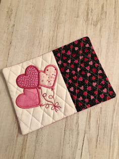 two hearts on black and pink quilted placemats, one with heart applique