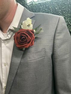 a man wearing a gray suit with a red and white flower on the lapel