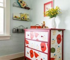 a red and white dresser with flowers painted on the drawers in front of a window