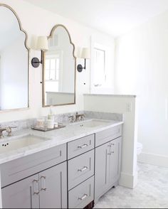 a bathroom with two sinks, mirrors and lights on the wall above them is shown