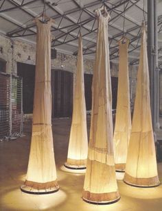 several tall wooden poles with lights on them in a room filled with concrete walls and flooring