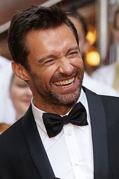 a man in a tuxedo smiles as he walks down the red carpet at an event