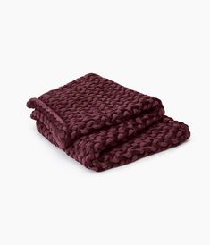 a blanket that is folded up on top of a white surface with a dark red color