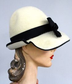 Mr. John does it again, with this exceptionally styled vintage chapeaux in ivory fur felt ( Angorette, made in Italy) with black grosgrain hatband and bow. The Cream Brimmed Cloche Hat For Evening, White Fitted Retro Hat, Classic Cream Evening Hat, Vintage Cream Felt Hat With Short Brim, White Curved Brim Fur Felt Hat, Vintage White Cloche Hat With Short Brim, Vintage White Fedora Hat, Elegant White Fur Felt Hat, Classic White Fur Felt Hat