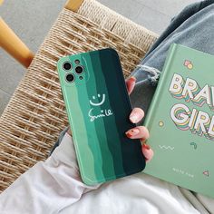 a person holding a phone case with a book in front of them on a chair