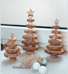 three small wooden christmas trees on top of each other with ornaments around the tree stumps