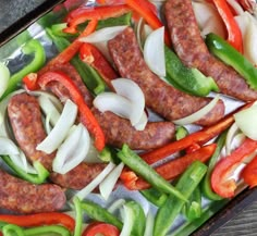 sausage and peppers on a sheet of tinfoil with onions, green peppers, and red bell peppers