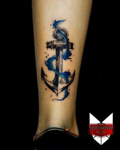 an anchor tattoo on the ankle with watercolor splashes and blue ink in it