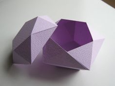 an origami box sitting on top of a white table next to a purple object