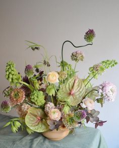 a vase filled with lots of flowers sitting on top of a green cloth covered table