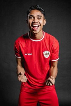 a young man in a red soccer uniform with his hands on his hips and mouth wide open