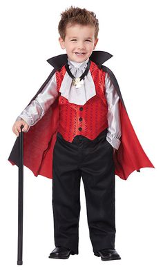 a little boy dressed in a dracula costume and holding a cane, smiling at the camera