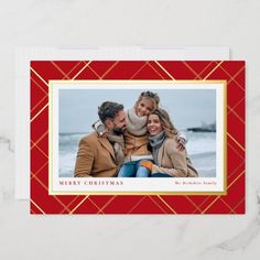 a red and gold christmas card with an image of two people hugging each other on the front