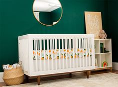 a white crib in front of a green wall with a mirror on the wall