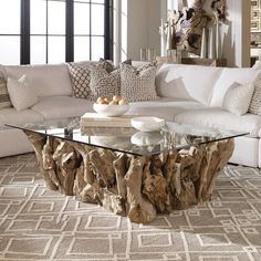 a living room filled with furniture and a glass top table in front of a white couch