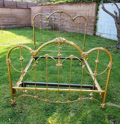 a gold metal bed frame sitting in the grass