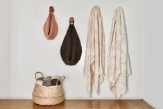 three towels hanging on the wall next to a basket with two umbrellas in it