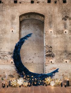 a large blue feathered object sitting on top of a brick floor next to candles