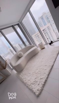 a living room filled with white furniture and tall windows