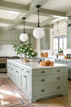 a large kitchen with green cabinets and white counter tops, along with an island in the middle