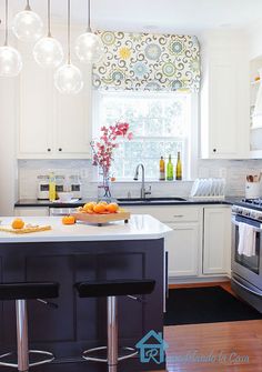 a kitchen with white cabinets and an island in front of a stove top oven next to a window