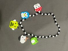 an image of pac - man and mario bros beaded necklaces on a table