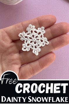 a hand holding a crochet snowflake on top of a purple surface