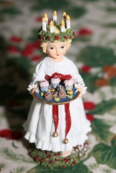 a small figurine holding a plate with cupcakes on it and candles