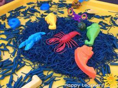 a yellow plastic tray filled with blue and orange string art toys on top of a table