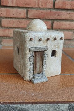 a small white building sitting on top of a tile floor next to a brick wall