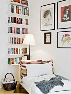 a white room with bookshelves and pictures on the wall, including a bed