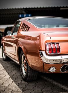 the rear end of an orange mustang parked in a parking lot