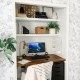 a computer desk with a monitor on top of it in front of a white wall