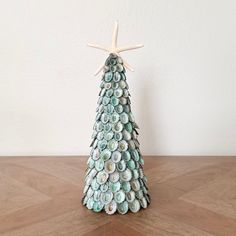 a small christmas tree made out of seashells and starfish shells on a wooden table