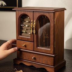 a wooden cabinet with jewelry in it on a table