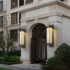 an entrance to a large building with two lamps on the front and one light on the side