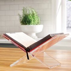 an open book sitting on top of a wooden table next to a potted plant