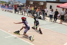 two people on roller blades in the middle of a court with spectators watching from behind