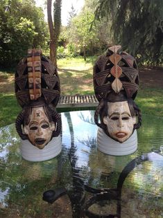 two ceramic masks sitting on top of a glass table