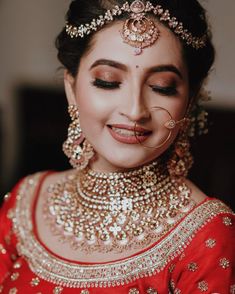 a woman in red and gold outfit with jewelry on her head, smiling at the camera