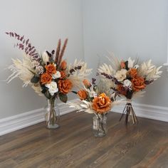 two vases filled with flowers on top of a wooden floor