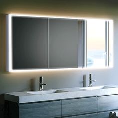 a bathroom vanity with two sinks under a mirror and lights on the wall above it