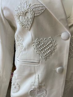 If you are going to give your heart away to your one true love, you better make sure that you are stocked with some to spare in the Any Old Iron True Love Suit. This white blazer and fit-and-flare trouser ensemble is covered in hand-beaded white hearts, where each one is different from the rest. The blazer comes with exterior pockets, a button, and a satin interior lining. The trousers, also, have the interior lining as well the matching design all throughout. It is the perfect little number for Pearl Suit, Wedding Suit Women, Embroidery Blazer, Beaded Blazer, Embellished Blazer, Jackets Style, Bridal Suits, Suit Embroidery, Satin Suit