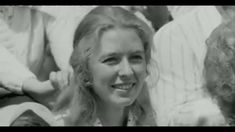 a black and white photo of a woman with long blonde hair smiling at the camera