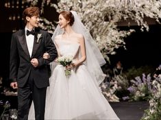 a man and woman in formal wear walking down the catwalk at a wedding ceremony