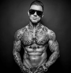 a man with tattoos on his chest wearing sunglasses