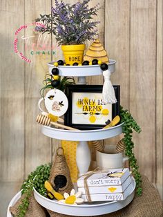 a three tiered shelf with flowers and other items on it, including a bee sign