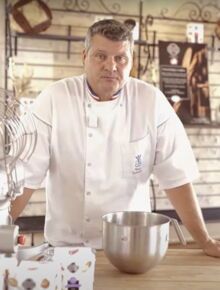 a man standing in front of a kitchen counter next to a mixing bowl and mixer